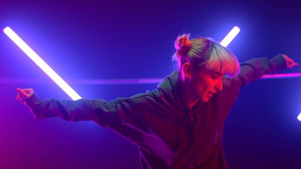 Neon ışıklarda serbest dans eden kadın. Sarışın ultraviyole ışıkta atlıyor. - Fotoğraf, Görsel