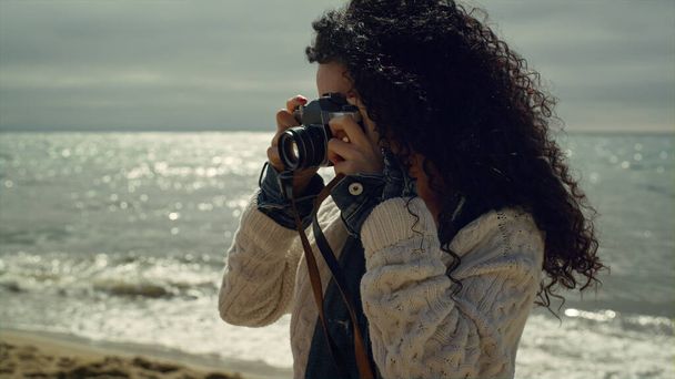 Mujer hispana tomando fotos en la orilla del mar. Bella dama fotografiando la naturaleza. - Foto, imagen