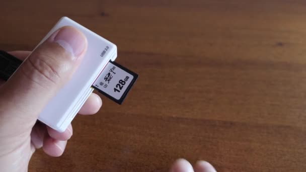 The man inserts a 128GB SD card into the card reader. Media for transmission and storage of information. Information Technology. - Footage, Video