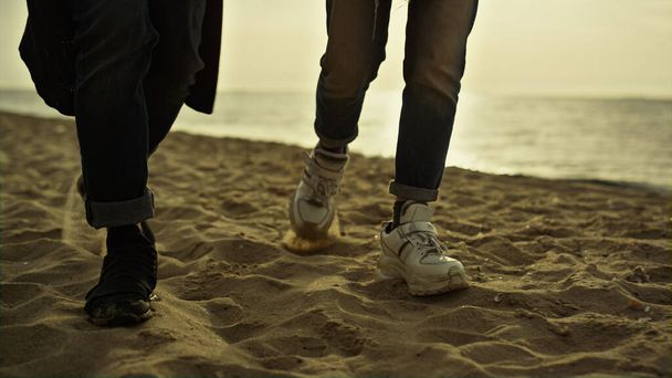 Les gens jambes marchent plage de sable au coucher du soleil vacances en mer. Couple marchant sur la rive. - Photo, image