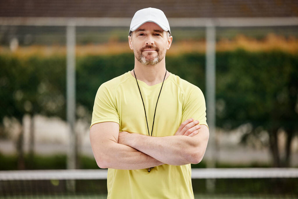 Hes one confident coach. Cropped portrait of a handsome mature male tennis coach standing with his arms folded on the court. - Photo, Image