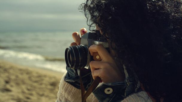 Bella signora scattare foto sulla spiaggia di mare. Donna etnica utilizzando fotocamera vintage. - Foto, immagini