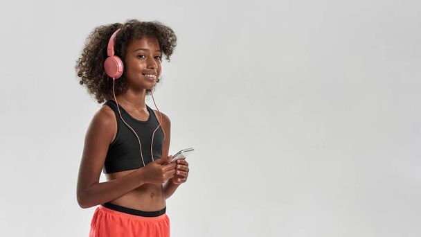 Smiling girl listening music in earphones on phone - Foto, Imagem