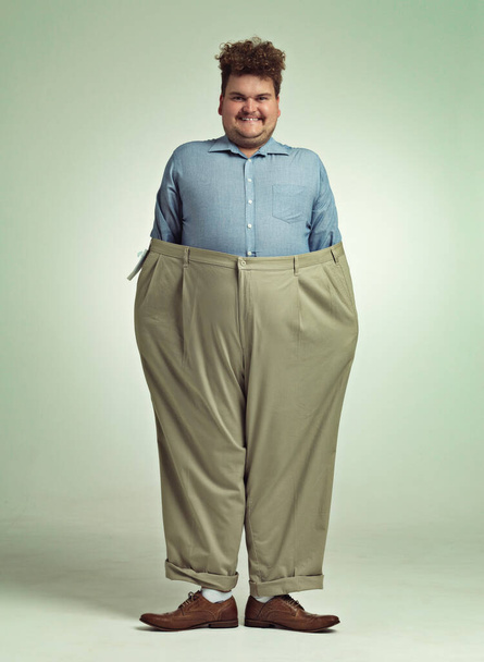 Progresso da dieta. Tiro de um homem com excesso de peso usando um par de calças grandes parecendo satisfeito. - Foto, Imagem