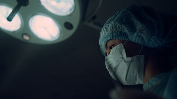 Portret verpleegkundige uitvoeren van operatie met medische klem in de operatiekamer. - Foto, afbeelding