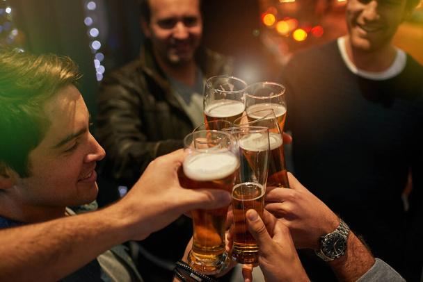 To nights like these. High angle shot of guys toasting with beers at a party. - Foto, imagen