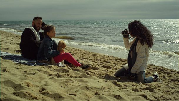 Γλυκιά οικογένεια απολαμβάνουν photosession στην άμμο παραλία. Γονιός παιδί ποζάρουν εικόνα από τη θάλασσα. - Φωτογραφία, εικόνα