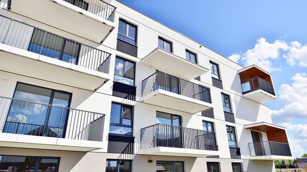 Balkonları ve bulutlu mavi gökyüzü olan beyaz bir yerleşim yerinin parçası. Güneşli bir günde modern apartmanda mimari detaylar. - Fotoğraf, Görsel