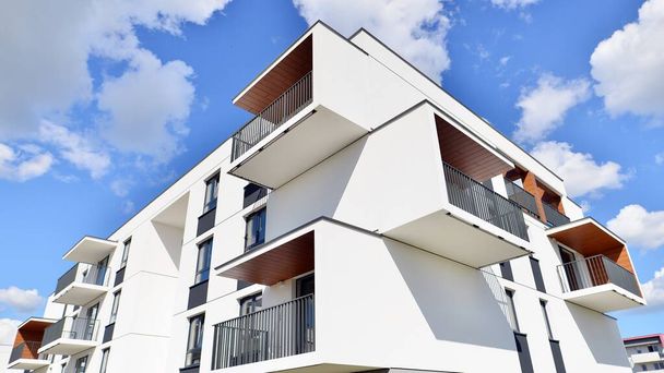 Частина білої житлової будівлі з балконами і блакитним небом з хмарами. Архітектурні деталі в сучасному багатоквартирному будинку на сонячний день
. - Фото, зображення