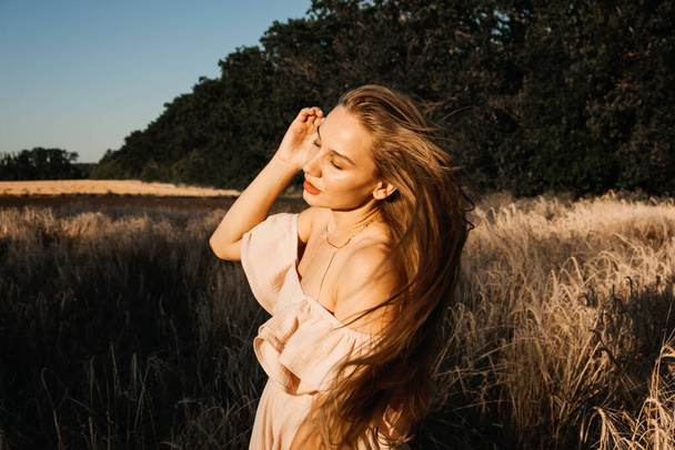 Get into wild, connect to nature. Happy woman enjoying life and nature on sunset wheat field. Outdoors portrait of beautiful confident woman laughing in nature - Foto, Bild