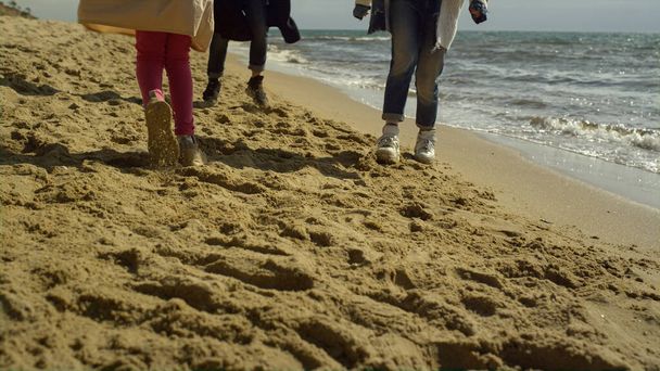 Playful family walking beach by sea sand. Excited people legs run around outside - Φωτογραφία, εικόνα