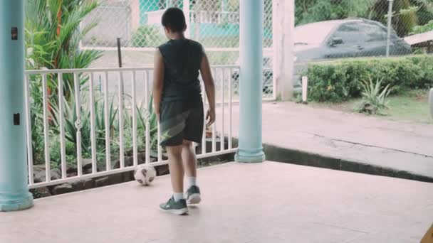 Latin boy kicking the ball against the railing - Footage, Video