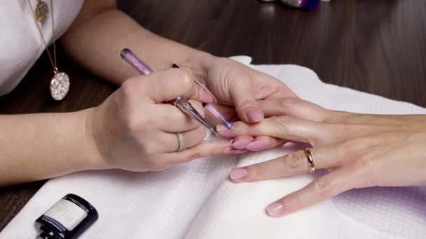 Esmalte de uñas. El primer plano del esmalte de uñas con las manicuristas. - Metraje, vídeo
