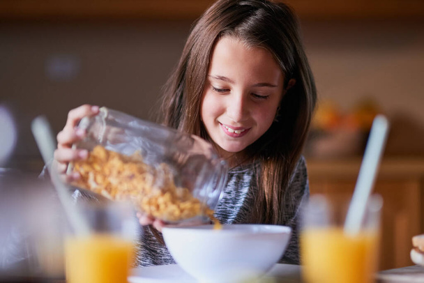 She loves cereal for breakfast, lunch and dinner. Cropped shot of a young girl pouring cereal into a bowl by herself. - Zdjęcie, obraz