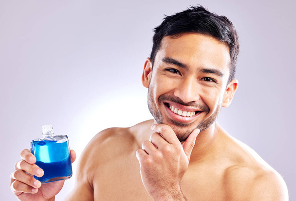 Everyone likes to smell good. Studio shot of a handsome young man applying aftershave. - Foto, Imagen