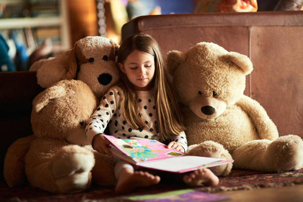A ler-lhe uma história. Tiro de uma menina lendo um livro com seus ursinhos de pelúcia em torno dela. - Foto, Imagem