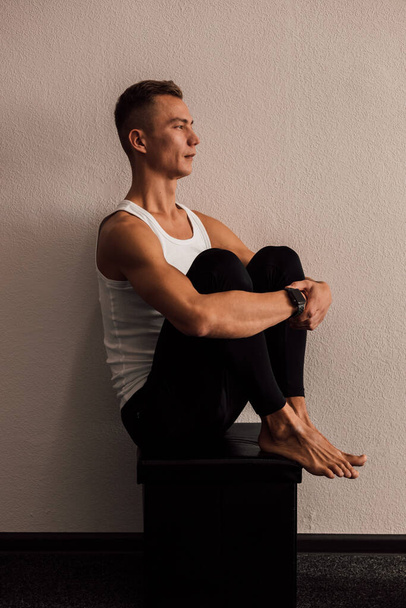 A man doing yoga holds his legs with his hands - Foto, Imagen