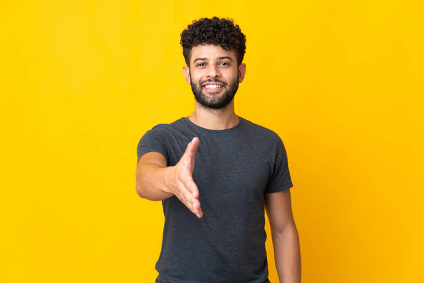 Young Moroccan man isolated on yellow background shaking hands for closing a good deal - Foto, immagini
