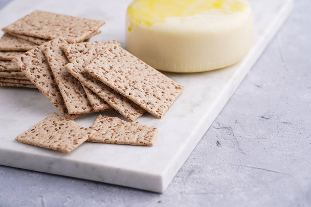 Sağlıklı çıtır çıtır krakerler susam tohumlu ve mermer tahtada yuvarlak peynirli kaş kaval. - Fotoğraf, Görsel