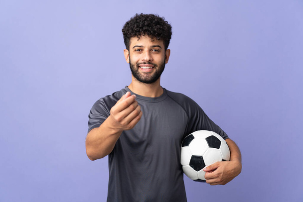 Handsome Moroccan young football player man over isolated on purple background making money gesture - Foto, imagen