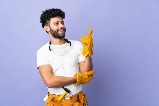 Young electrician Moroccan man isolated on purple background pointing up a great idea - Foto, Bild