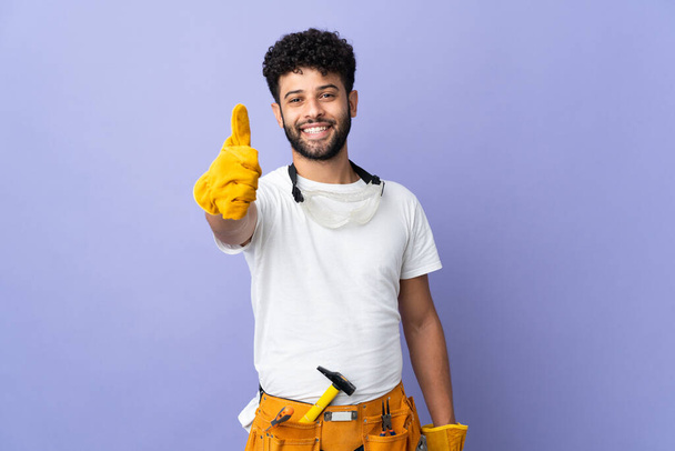 Young electrician Moroccan man isolated on purple background with thumbs up because something good has happened - Fotografie, Obrázek