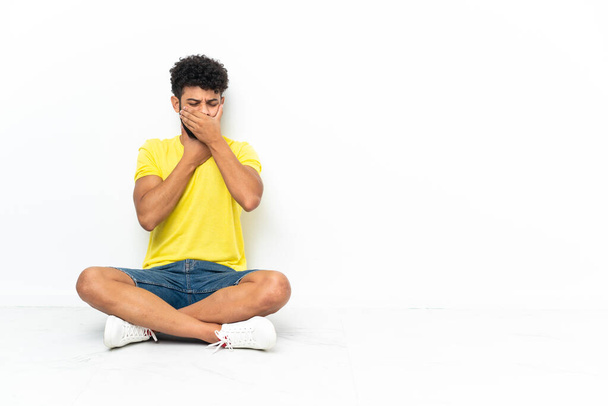 Young Moroccan handsome man sitting on the floor over isolated background is suffering with cough and feeling bad - Фото, изображение