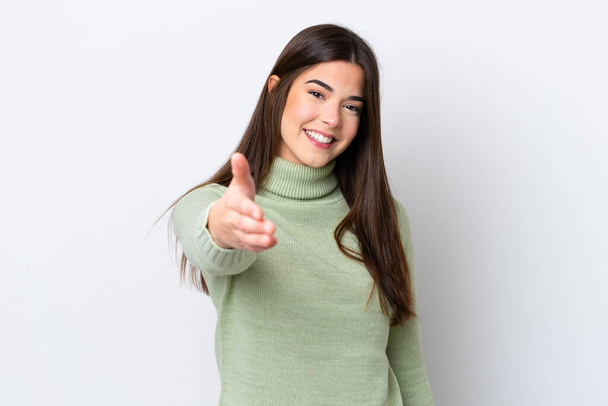 Young Brazilian woman isolated on white background shaking hands for closing a good deal - Фото, зображення