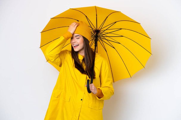 Young Brazilian woman with rainproof coat and umbrella isolated on white background has realized something and intending the solution - Foto, afbeelding