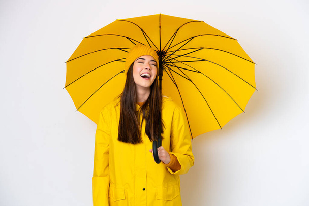Молода бразильська жінка з дощовитим пальто і парасолька ізольовані на білому фоні сміх - Фото, зображення