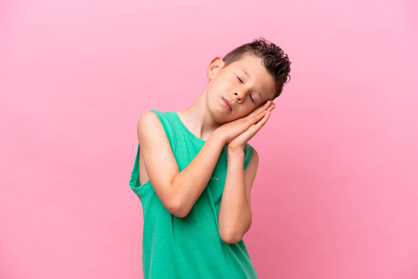 Little caucasian boy isolated on pink background making sleep gesture in dorable expression - Fotó, kép