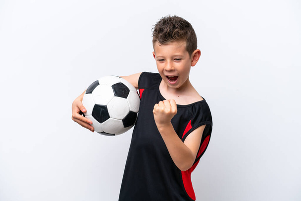 Pequeño chico caucásico aislado sobre fondo blanco con pelota de fútbol celebrando una victoria - Foto, imagen