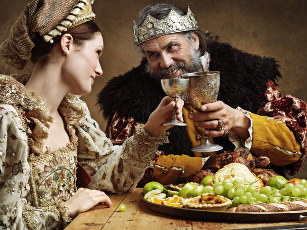 Tal vez una copa llena te anime, señora. Un rey maduro festejando solo en una sala de banquetes. - Foto, imagen