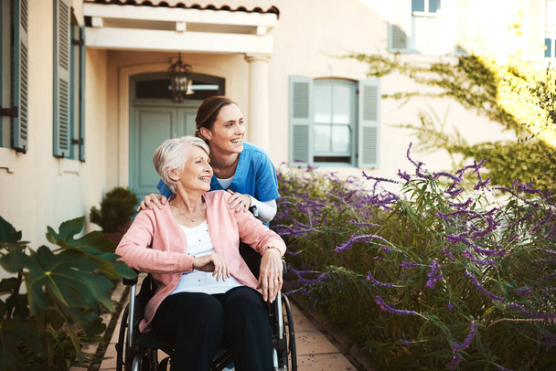 Spend your senior years living a relaxed life. Cropped shot of a young female nurse outside with a senior patient in a wheelchair. - Photo, Image