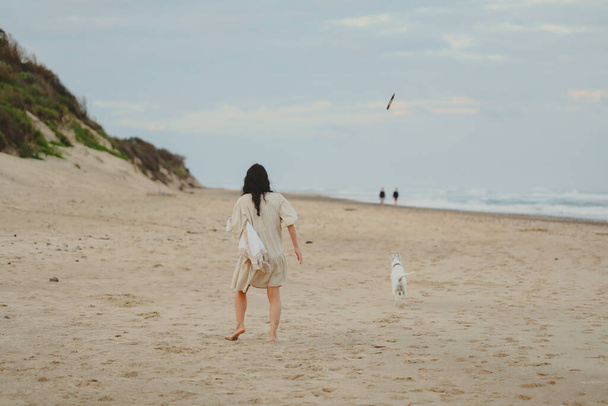 Mulher e cão correndo e jogando buscar na praia - Foto, Imagem