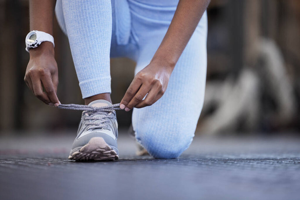 Make sure theyre secure before you begin. Closeup shot of an unrecognisable woman tying her laces in a gym. - Photo, Image