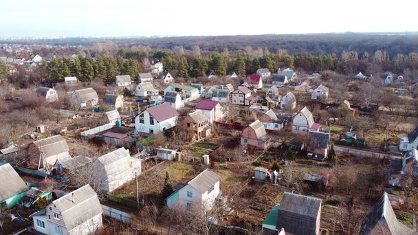Vuelo de vista aérea del dron sobre pequeñas casas de ladrillo con parcela de tierra en el medio - Foto, imagen