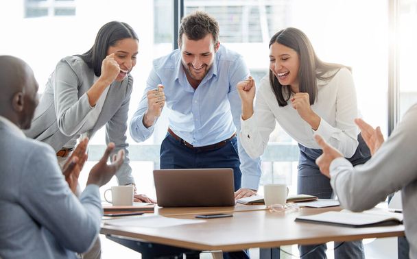 We can do this. Shot of a group of businesspeople cheering while using a laptop in an office at work. - Fotografie, Obrázek