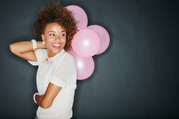 Πιστεύω ότι πρέπει να γίνουν εορτασμοί. Στιγμιότυπο ενός ελκυστικού νεαρή γυναίκα κρατώντας ένα μάτσο μπαλόνια σε ένα γκρι φόντο. - Φωτογραφία, εικόνα