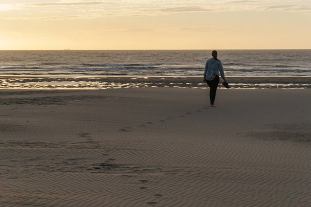 відбитки слідів у піску на пляжі під час золотої години на заході сонця
 - Фото, зображення