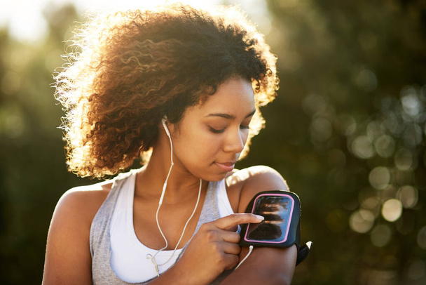 Выбери плейлист, который тебя заводит. Снимок привлекательной молодой женщины, слушающей музыку во время занятий на открытом воздухе. - Фото, изображение