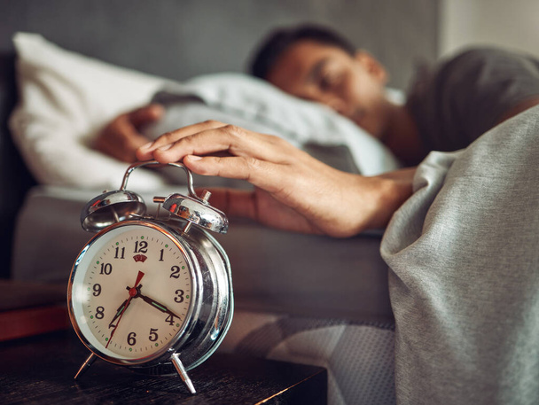 Just five more minutes, said no one ever. Shot of a young man reaching for his alarm clock after waking up in bed at home. - Photo, Image