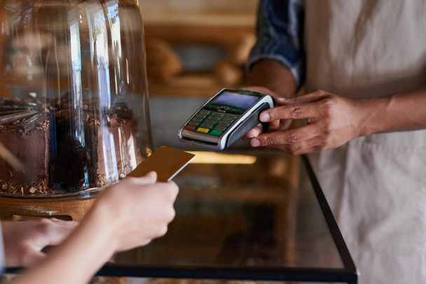 Ponlo en mi cuenta corriente. Primer plano de un cliente haciendo un pago con tarjeta de crédito en un café. - Foto, Imagen
