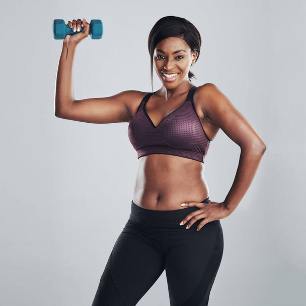 Strength mixed with beauty, what a combo. Studio portrait of an attractive and fit young woman exercising with a dumbbell against a grey background. - Fotó, kép
