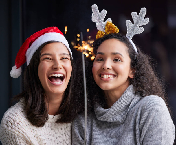 Celebrating Christmas with the right people. Shot of two best friends standing together and holding up a sparker while celebrating Christmas. - Fotoğraf, Görsel
