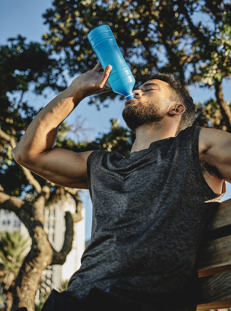 Это была отличная тренировка. Снимок спортивного молодого человека, пьющего воду на открытом воздухе. - Фото, изображение