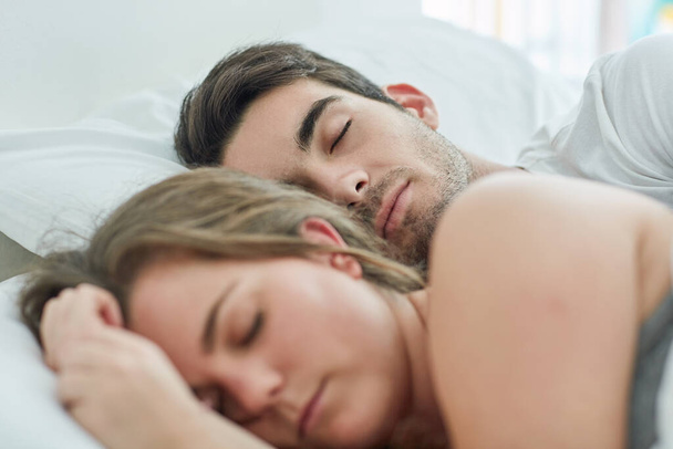 Pas besoin de se précipiter aujourd'hui. Tourné d'un jeune couple détendu dormant au lit ensemble à la maison. - Photo, image