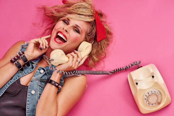 Everyone had so much fun in the 80s. Studio shot of a young woman holding a telephone while wearing 80s clothing. - Foto, Imagen