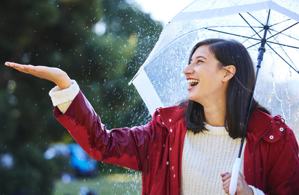 Está lloviendo fuerte. Un disparo de una joven mujer de pie bajo la lluvia con un paraguas. - Foto, imagen