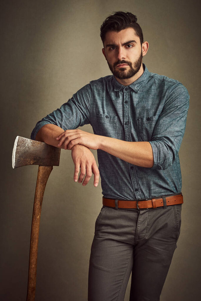 Tantalizingly tough. Studio shot of a young man posing with an axe against a green background. - Photo, Image